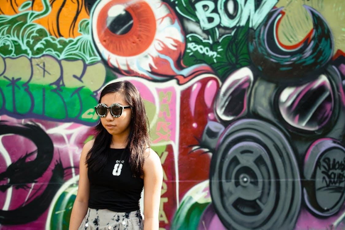 Woman In Black Top And Black Sunglasses Standing Beside Graffiti Wall